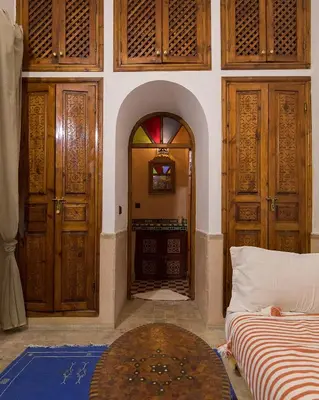 a room with wooden doors and a room with a bed at Riad Wardate Rita in Marrakech