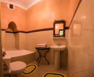 a bathroom with a sink and a toilet and a mirror at Riad Omar in Marrakech