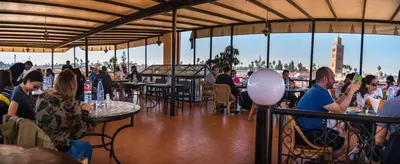 a group of people sitting at tables in a restaurant at Riad Omar in Marrakech