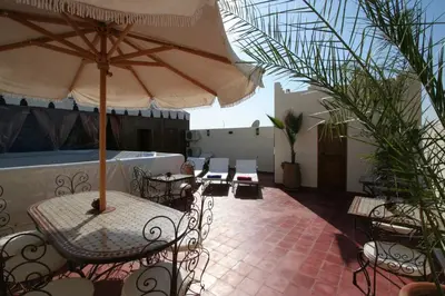 a patio with tables and chairs and an umbrella at Riad Morgane in Marrakech
