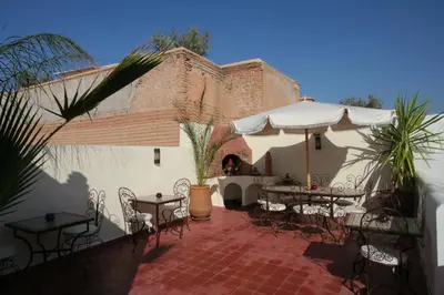 a patio with tables and chairs and an umbrella at Riad Morgane in Marrakech