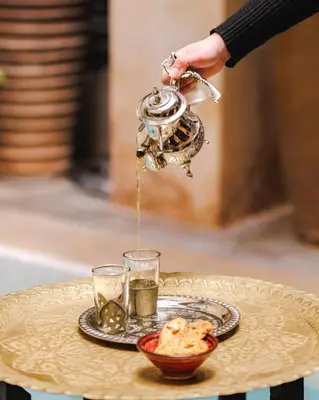 a person pouring tea from a tea kettle on a table at Dar Beija in Marrakech
