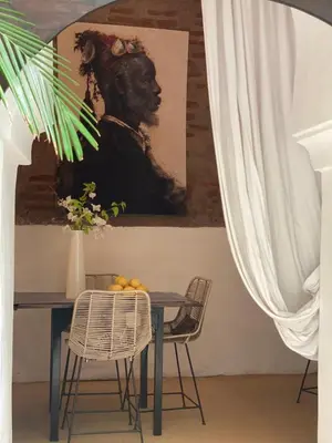 a dining room with a table with a painting on the wall at Riad Wabisabi in Marrakech