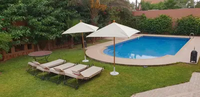 a group of chairs and umbrellas next to a pool at Villa clos Odette in Marrakech