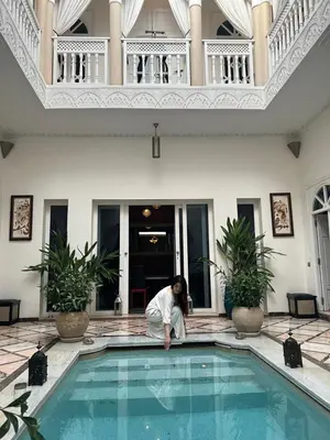 a woman is bending over a swimming pool at RIAD DREAMS in Marrakech