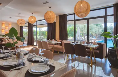a restaurant with tables and chairs and large windows at Boutique Hotel Katia in El Harkat