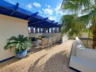 a patio with a table and chairs and a palm tree at Dar Al Kounouz in Marrakech