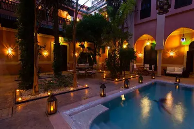 a swimming pool in the middle of a building with lights at Riad Le Perroquet Bleu Suites & Spa in Marrakech