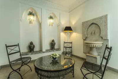 a room with a table and chairs and a fountain at Riad Le Perroquet Bleu Suites & Spa in Marrakech