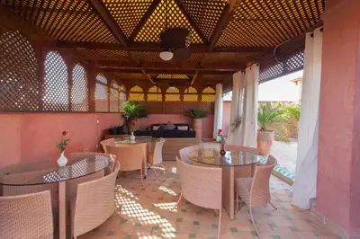 a patio with tables and chairs and a couch at Riad Le Perroquet Bleu Suites & Spa in Marrakech