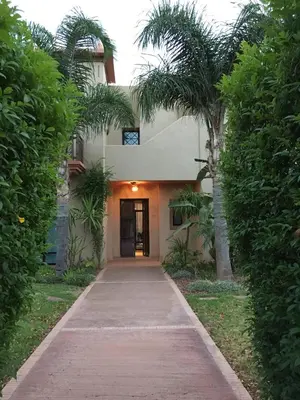 a walkway leading to a building with palm trees at Villa entière GOLF MARRAKECH in Marrakech