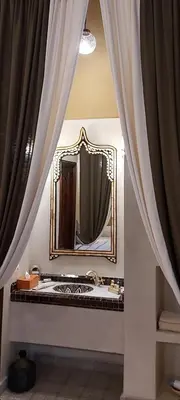 a bathroom with a mirror and some curtains at Riad Les Nuits de Marrakech in Marrakech