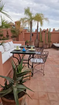 a patio with a table and chairs and palm trees at Riad Les Nuits de Marrakech in Marrakech
