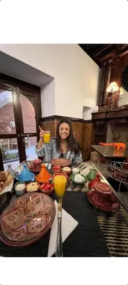 a woman sitting at a table with plates of food at Riad Les Nuits de Marrakech in Marrakech