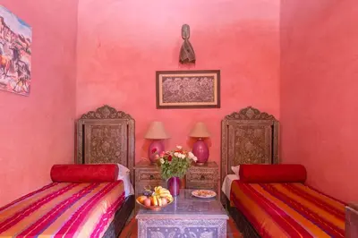 a pink room with two beds and a table at Riad Lalla Khiti in Marrakech