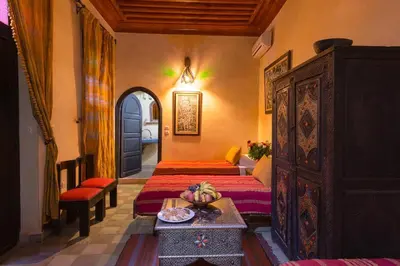 a bedroom with two beds and a table with a bowl of fruit at Riad Lalla Khiti in Marrakech
