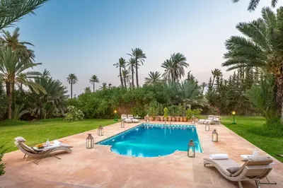 a swimming pool with chaise lounges and chairs around it at Domaine Rosaroum in Marrakech