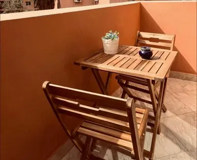 a wooden table and chairs with a potted plant on it at Cosy stays central apartements , guéliz Marrakech in Marrakech