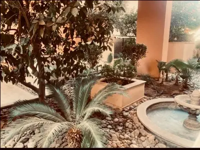 a garden with a fountain and palm trees in a building at Cosy stays central apartements , guéliz Marrakech in Marrakech