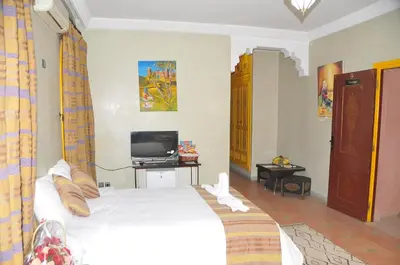 a bedroom with a white bed and a tv at Riad Mhidou in Marrakech