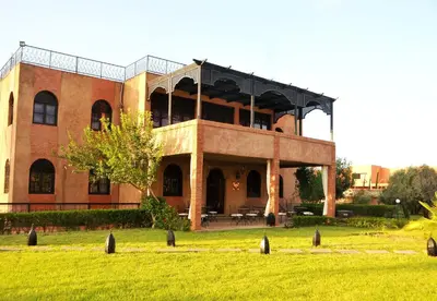a large brick building in a field of grass at Riad Mhidou in Marrakech