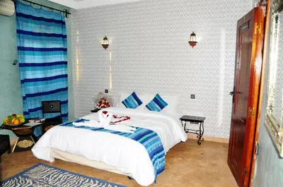 a bedroom with a large white bed with blue pillows at Riad Mhidou in Marrakech