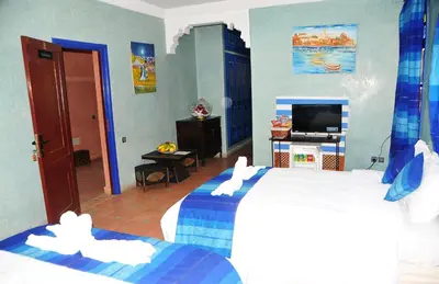a hotel room with two beds and a television at Riad Mhidou in Marrakech