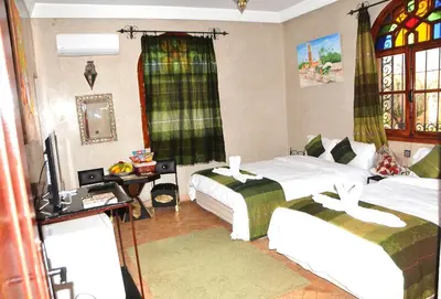 a bedroom with two beds and a tv in it at Riad Mhidou in Marrakech