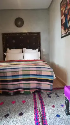 a bedroom with a bed with a colorful blanket on it at Riad Achwaq in Marrakech
