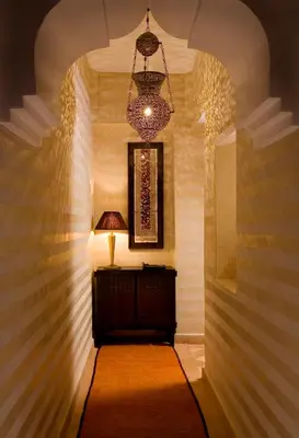 a hallway with a chandelier and a table with a lamp at Riad Meriem in Marrakech