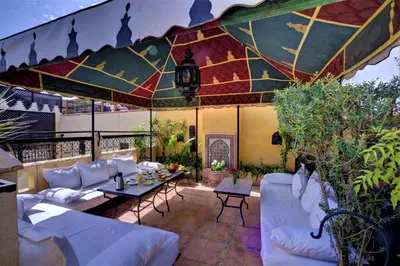 a patio with white couches and a table under an umbrella at Riad Dar El Souk in Marrakech