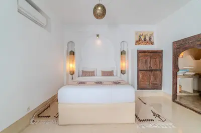 a white bedroom with a white bed and a mirror at Riad Ayla avec Piscine Privée in Marrakech