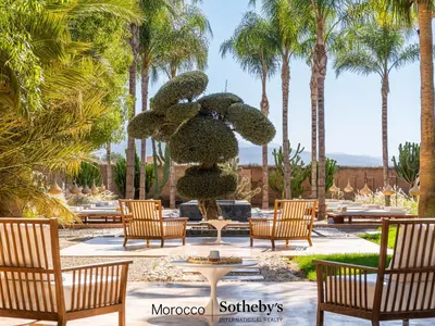 a fountain in a courtyard with chairs and palm trees at Villa Taj Marrakech in Marrakech