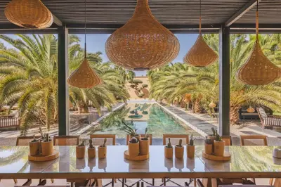 a dining room with a view of a pool and palm trees at Villa Taj Marrakech in Marrakech