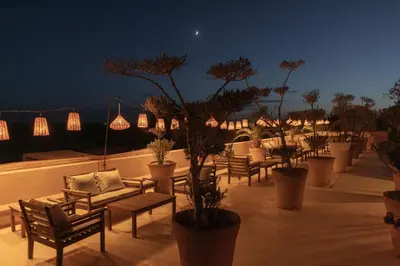 a patio with chairs and potted trees at night at Villa Taj Marrakech in Marrakech