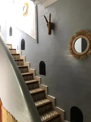 a stairway with a mirror and areath on a wall at Riad Bab Lakhmiss in Marrakech
