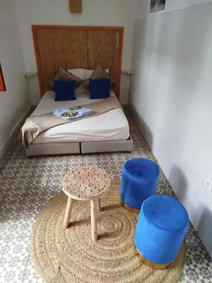 a bedroom with a bed with blue stools and a table at Riad Bab Lakhmiss in Marrakech