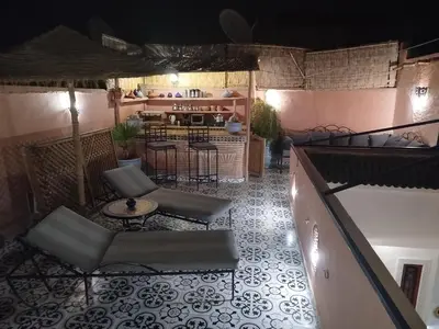 an outdoor patio with chairs and tables and a bar at Riad Bab Lakhmiss in Marrakech