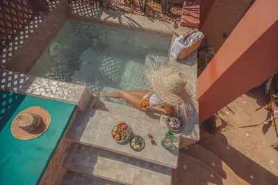 an overhead view of a woman laying next to a swimming pool at Riad Le Limoun and Spa in Marrakech