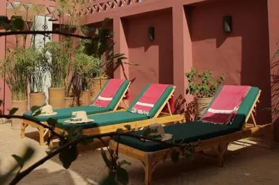 two lounge chairs sitting on a patio in front of a pink building at Riad Le Limoun and Spa in Marrakech