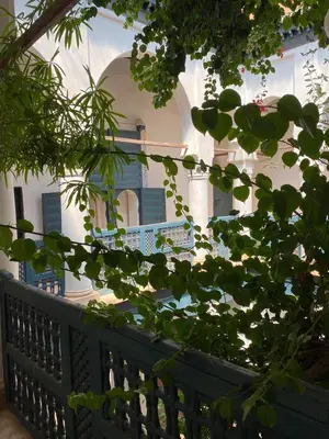 a white building with blue shutters and a fence at Dar El Qadi in Marrakech