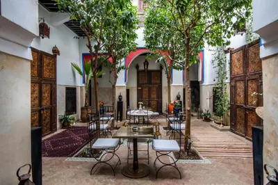 a courtyard with tables and chairs and trees at Riad dar Ourika & SPA in Marrakech