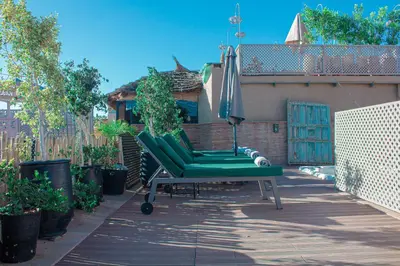 a green chair and an umbrella on a patio at Riad Al Rimal & Spa in Marrakech