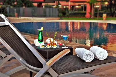 a table with a drink and towels next to a pool at Rawabi Hotel Marrakech & Spa in Marrakech