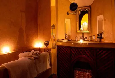 a bathroom with a fireplace and a sink and a mirror at Dar Les Cigognes in Marrakech
