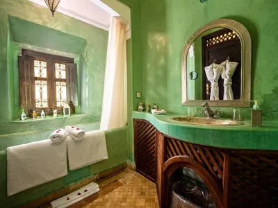 a green bathroom with a sink and a mirror at Dar Les Cigognes in Marrakech