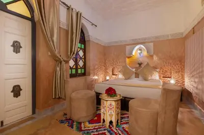 a bedroom with a bed and two chairs and a door at Riad Kech Soul Boutique & Spa in Marrakech