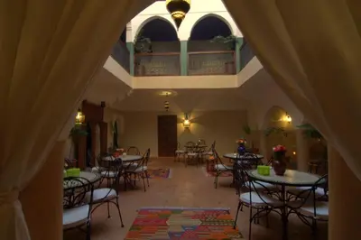 a restaurant with tables and chairs and a balcony at Riad Imilchil in Marrakech