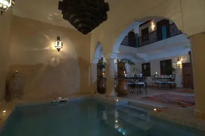 an indoor swimming pool in a building with a house at Riad Imilchil in Marrakech