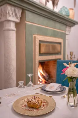 a table with a plate of food and a fireplace at Riad Khalifa in Marrakech